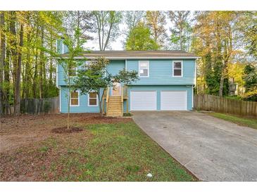 Charming two-story home with a light blue exterior, a well-maintained lawn, and an attached two-car garage at 5030 Sumit Wood Dr, Kennesaw, GA 30152