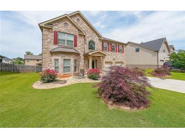 Charming brick home with a well-manicured lawn, beautiful flower beds, and a two-car garage at 8097 White Oak Loop, Lithonia, GA 30038