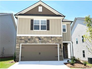 Two-story home featuring stone accents, beige siding, a two-car garage, and a well-maintained lawn at 258 Station Overlook Dr, Auburn, GA 30011