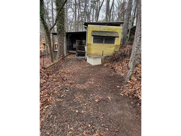 Exterior view of a single wide mobile home nestled among trees in a rustic setting at 1000 Delta A15, Canton, GA 30114