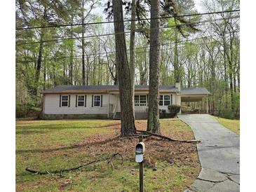Charming single-story home with a covered carport and an asphalt driveway nestled among mature trees at 7508 Asbury Manor Dr, Lithonia, GA 30058