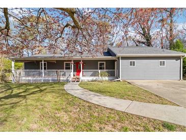 Charming gray home with a welcoming front porch, red door, and manicured lawn offers great curb appeal at 1354 Litchfield Ct, Snellville, GA 30078