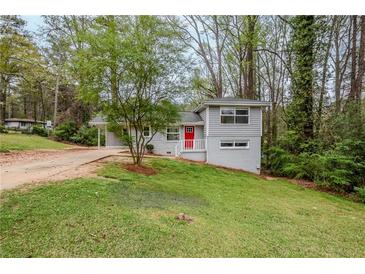 Charming gray split level home with a bright red front door and a lush green lawn at 3436 Misty Valley Rd, Decatur, GA 30032