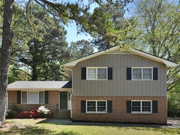 Charming two-story home featuring a brick and siding facade, complemented by lush landscaping and a well-manicured lawn at 5470 Chanterella Sw Ct, Lilburn, GA 30047