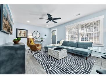 Bright living room with a modern blue sofa, stylish rug, and plenty of natural light from the large window at 2535 Judson Ave, East Point, GA 30344