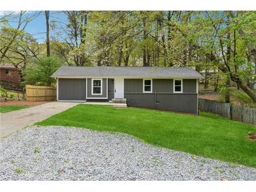 Charming single-story home with a gray exterior, fresh green lawn, and a gravel driveway at 2115 Randolph Nw Cir, Kennesaw, GA 30144