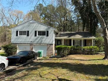 Charming home featuring a two-car garage, brick accents, and mature landscaping in a serene, wooded setting at 2521 Rockknoll Dr, Conley, GA 30288