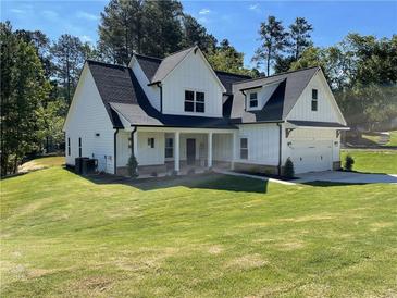 Charming two-story white farmhouse with a well-manicured lawn and welcoming front porch at 1698 Cunningham Sw Rd, Marietta, GA 30008