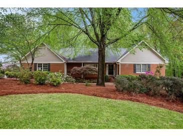 Charming single-story home with brick facade, lush landscaping, and mature trees on a well-maintained lawn at 1235 Saint Ives Ct, Suwanee, GA 30024