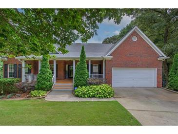Charming brick home with a well-manicured lawn, inviting front porch, and a two car garage at 51 Muirfield Ct, Hiram, GA 30141