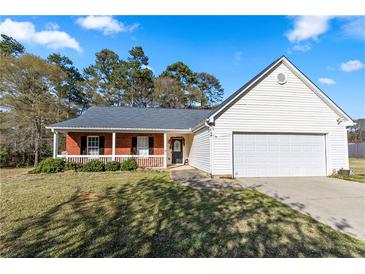 Charming single-story home with brick accents, a covered porch, and a two-car garage at 704 Manor Ridge Dr, Loganville, GA 30052