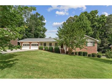Charming brick home featuring a two-car garage, well-maintained lawn, and lush greenery at 4135 Shoshone Valley Rd, Marietta, GA 30068