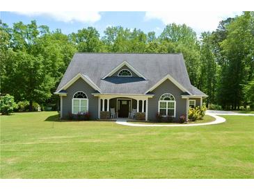 Charming grey home with a manicured lawn, inviting front porch, and meticulously maintained landscaping at 3440 Camelot Way, Loganville, GA 30052