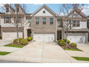 Attractive townhome with a two-car garage, a brick facade, a concrete driveway, and tasteful landscaping at 7554 Roseberry Way, Lithonia, GA 30038