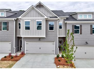 Charming townhome featuring a two-car garage, gray brick facade, and craftsman-style accents at 1357 Fern Ridge Ct # 30, Norcross, GA 30093