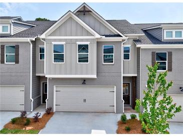 Stylish two-story townhome featuring a gray brick facade, attached garage, and inviting front entrance at 1357 Fern Ridge Ct # 30, Norcross, GA 30093