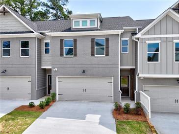 Modern townhome with a gray brick facade, complemented by a neutral gray garage door and manicured landscaping at 1387 Fern Ridge Ct # 33, Norcross, GA 30093