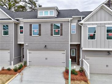 Charming townhome featuring a gray brick facade, attached garage, and well-maintained landscaping at 1387 Fern Ridge Ct # 33, Norcross, GA 30093