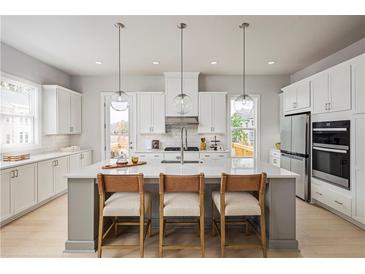 Bright kitchen features white cabinetry, quartz countertops, stainless steel appliances, and pendant lighting at 2625 Camphor Se Xing # 86, Smyrna, GA 30080