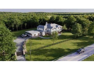 Stunning aerial view of a white farmhouse-style home with long driveway and lush green surroundings at 4385 Hickory Flat Hwy, Canton, GA 30115