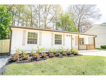 Charming one-story home with a well-manicured lawn, fresh flowers, and natural wood porch accents at 716 Sunfield Nw Dr, Lilburn, GA 30047
