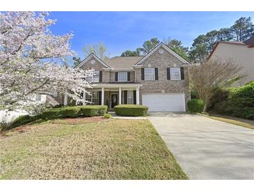Traditional two-story brick home featuring a well-manicured lawn, attached garage, and charming front porch at 140 Kirkland Dr, Lawrenceville, GA 30044