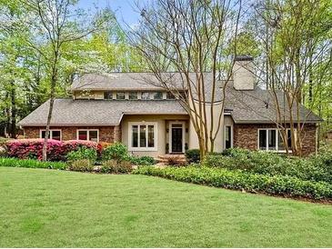 Charming exterior view of a stone and stucco home with a manicured lawn and mature trees at 420 Longs Peak, Johns Creek, GA 30022