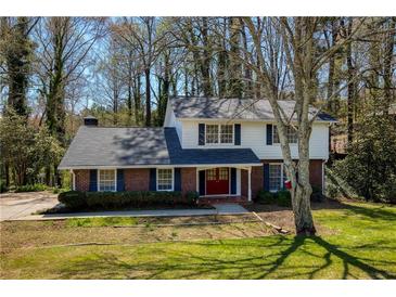 Charming two-story home with brick facade, a well-manicured lawn, mature trees and dark shutters at 520 Willeo Rd, Roswell, GA 30075