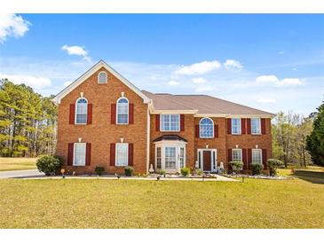 A well-maintained brick home with red shutters and a manicured front lawn at 859 Pownal Ln, Hampton, GA 30228