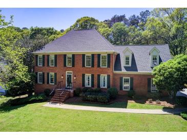 Beautiful two-story brick home with green shutters and a well-manicured lawn and mature trees at 5162 Charlemagne Sw Way, Lilburn, GA 30047