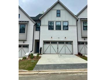 Charming townhome with a painted white brick facade and a two-car garage at 138 Briargate Dr, Johns Creek, GA 30097