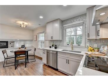 Well-lit kitchen featuring stainless steel appliances, white cabinets, and a cozy breakfast nook at 1450 Cedarhurst Dr, Dunwoody, GA 30338