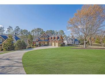 Beautiful brick home boasts a three-car garage and a lush green lawn, perfect for outdoor enjoyment at 6925 Lighthouse Point, Cumming, GA 30041