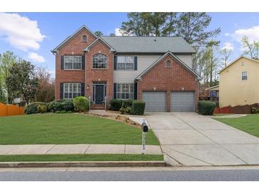 Beautiful two-story brick home with a well-manicured lawn and a two-car garage at 5280 Oak Hill Ter, Cumming, GA 30040