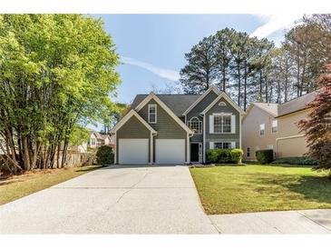Charming two-story home with a two-car garage, manicured lawn, and mature trees at 1855 Keswick Place Dr, Lawrenceville, GA 30043