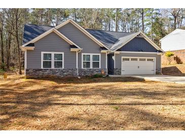 Charming gray home with stone accents and a two-car garage provides comfortable living in a serene setting at 5328 Monticello Dr, Villa Rica, GA 30180