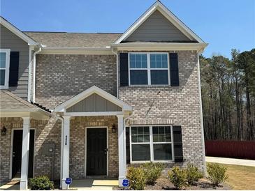 Charming townhome featuring a brick facade, black shutters, and well-maintained landscaping at 6420 Olmadison Pl, Atlanta, GA 30349