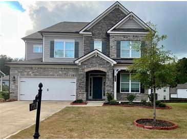 Charming two-story home with a stone and brick facade and well-manicured lawn at 7665 Easton Valley Ln, Cumming, GA 30028