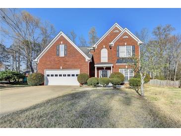 Charming two-story brick home featuring a manicured front lawn, attached garage, and symmetrical design elements at 1824 Kristen Ct, Suwanee, GA 30024
