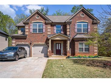 Charming two-story brick home with a two-car garage, lush lawn, and tasteful landscaping at 5761 Sawgrass Cir, Lithonia, GA 30038