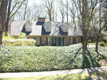 Charming brick home featuring dormer windows, a well-maintained lawn, and lush landscaping at 993 Castle Falls Dr. Ne Dr, Atlanta, GA 30329