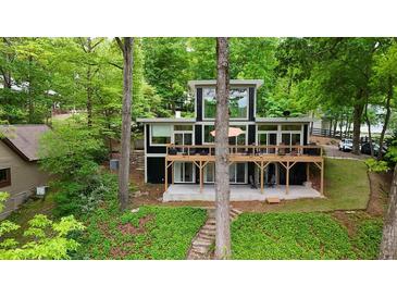 Contemporary two-story home with large windows and spacious deck surrounded by lush greenery and mature trees at 132 Lakeshore Dr, Roswell, GA 30075