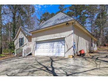 Beige home with a white garage door and stairs in a partially-wooded, residential neighborhood at 4186 Argonne Dr, Villa Rica, GA 30180