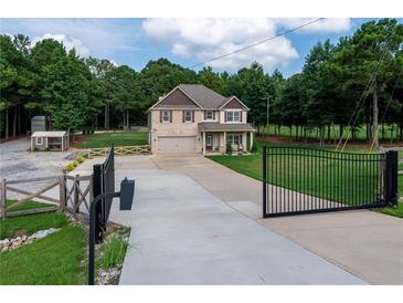 Two-story home featuring a manicured lawn, driveway, and gated entrance set against a lush backdrop of mature trees at 1585 Elliott Rd, Mcdonough, GA 30252