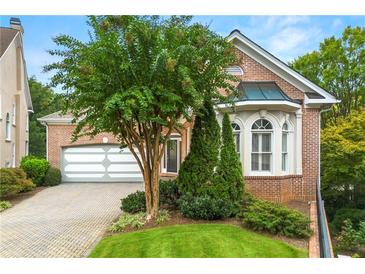 Charming brick home showcasing a well-maintained lawn and brick driveway leading to a two-car garage at 1079 Arbor Ne Trce, Atlanta, GA 30319