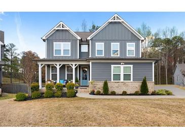 Charming two-story home featuring gray siding, a brick base, manicured landscaping and a welcoming front porch at 29 Laurelwood Nw Ln, Cartersville, GA 30121