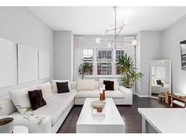 Bright living room with a large white sectional sofa, modern light fixture, and dark hardwood floors at 3933 Danube Ln # 224, Atlanta, GA 30339