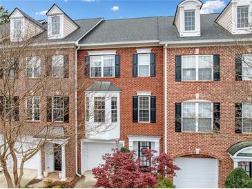 Charming brick townhome featuring a bay window, dormers, black shutters, and a two-car garage at 4908 Waters Edge Trl, Roswell, GA 30075