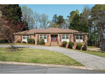 Charming single-story brick home with manicured lawn and mature trees, plus a long driveaway at 2223 Jay Se Ln, Smyrna, GA 30080