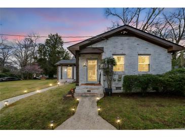 Charming white brick home with inviting walkway lighting and well-maintained lawn at dusk at 1780 John Calvin Ave, Atlanta, GA 30337